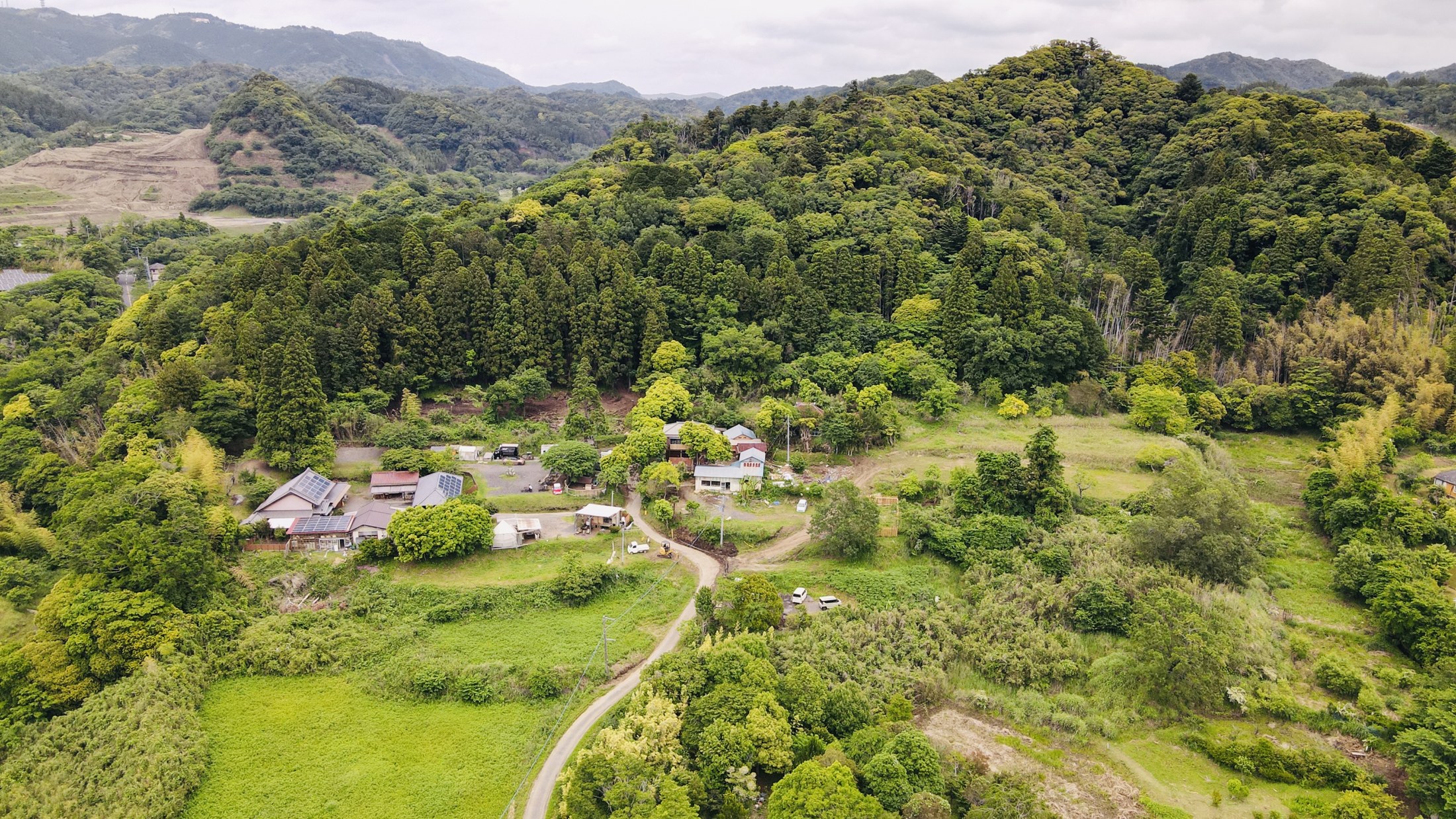 山の緑に囲まれ、建物やテントが点在する千葉県富津市の和心村