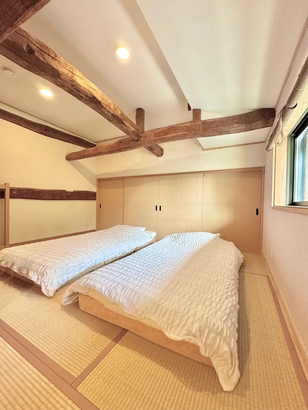 古い木の梁と畳、二つのベッドがある和心村の長屋門の客室